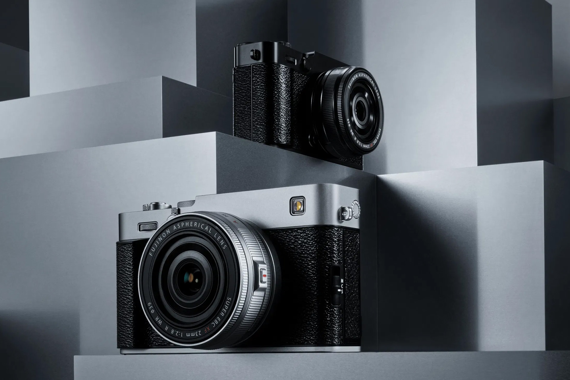 レンズキット「XF23mmF2.8 R WR」を装着した富士フイルム X-E5のシルバーとブラックのモデルが、スタイリッシュな背景に置かれている。