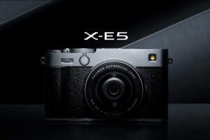 富士フイルムの最新ミラーレスカメラ「X-E5」のシルバーモデルの正面からのクローズアップ画像。アルミ削り出しの美しい軍艦部と、XF23mmレンズが装着されている。