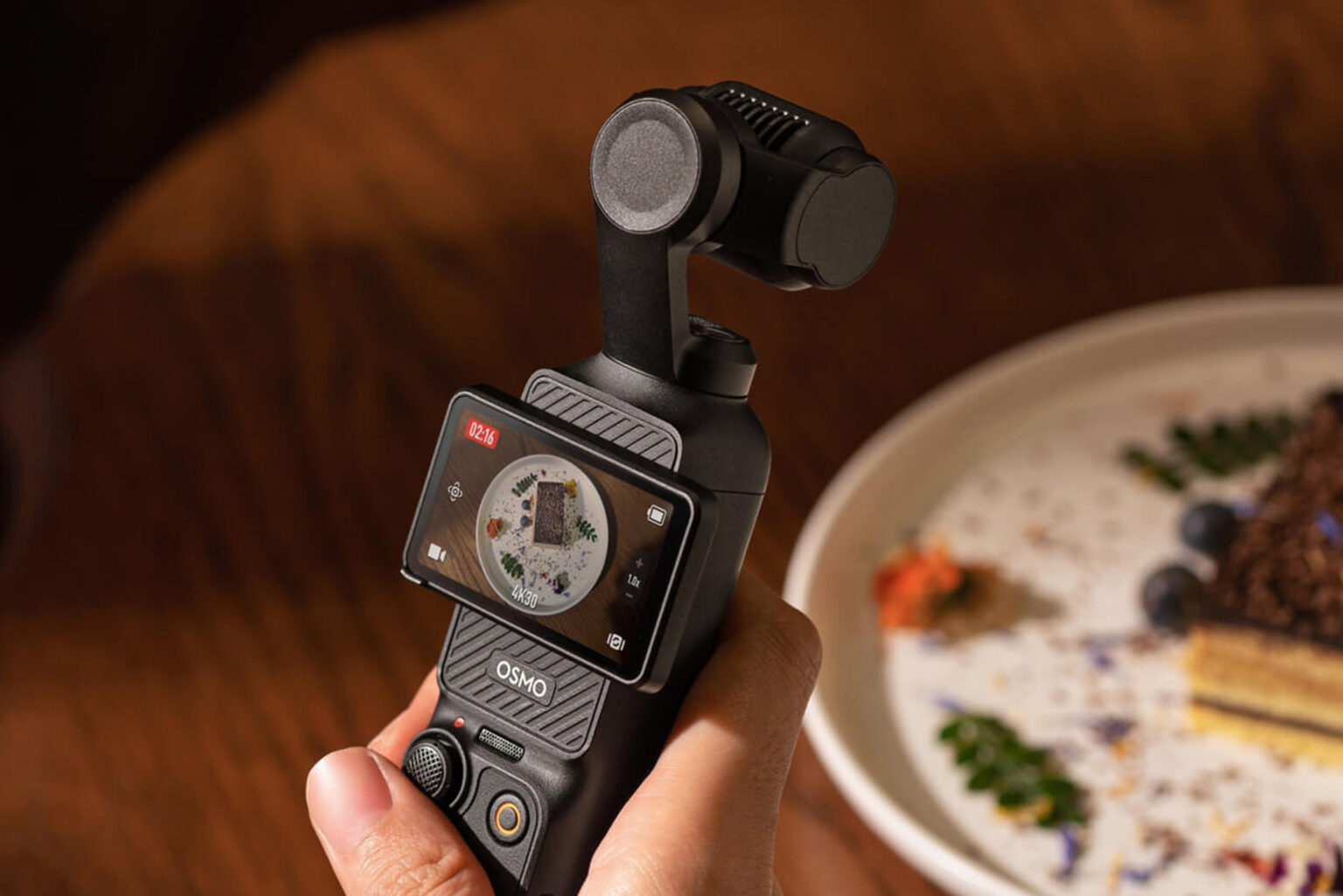 DJI Osmo Pocket 3を手に持ち、テーブルの上のデザートを撮影している様子。次期モデルOsmo Pocket 4の噂記事のアイキャッチ画像。